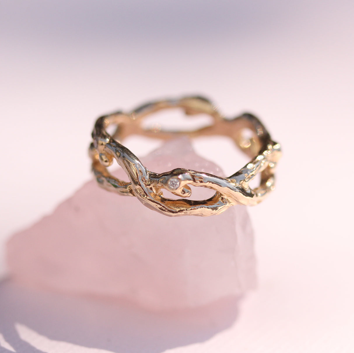 Intertwined branch style wedding band in yellow gold with diamonds and emerald