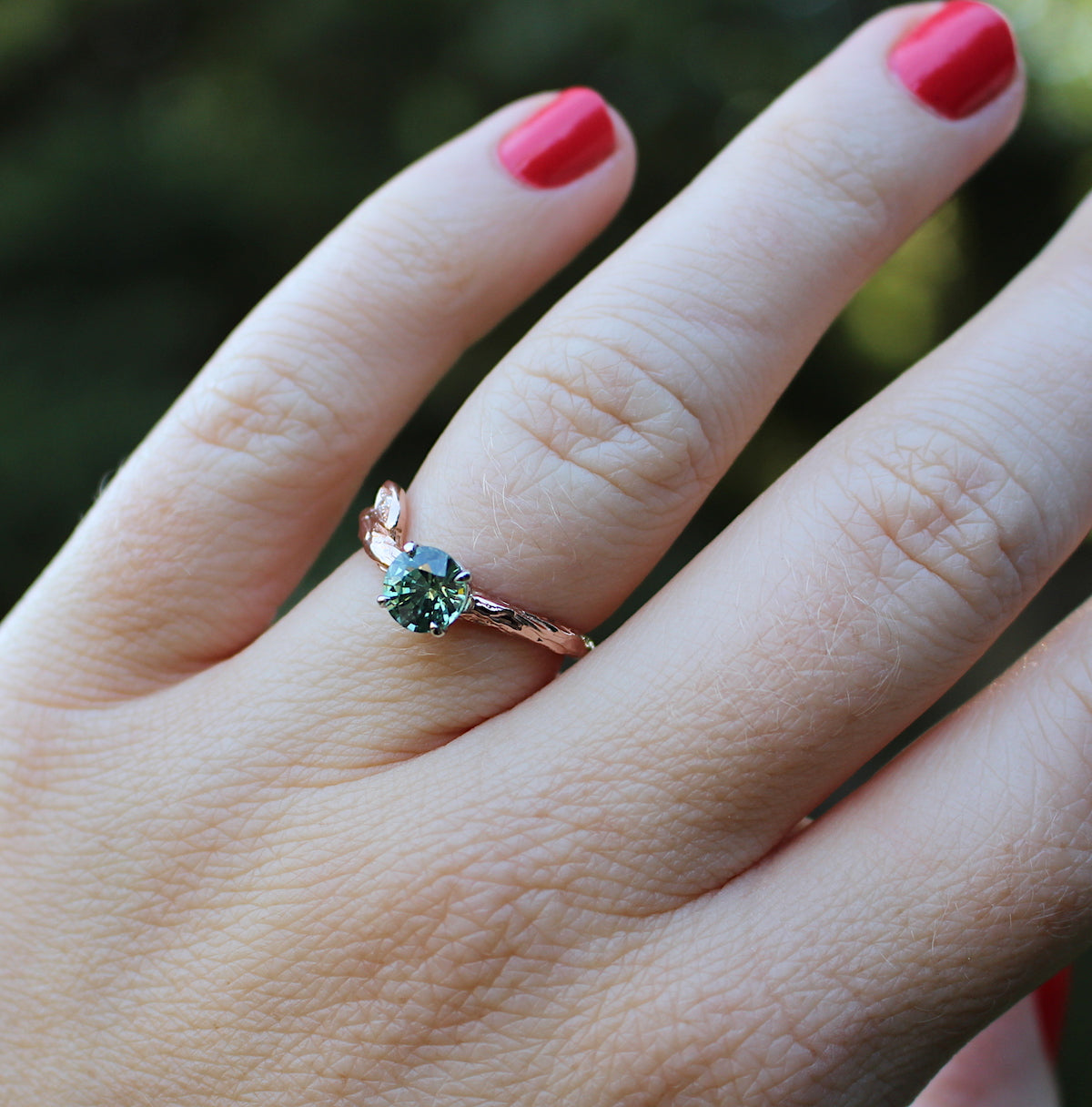 Green sapphire and rose gold ring on a hand