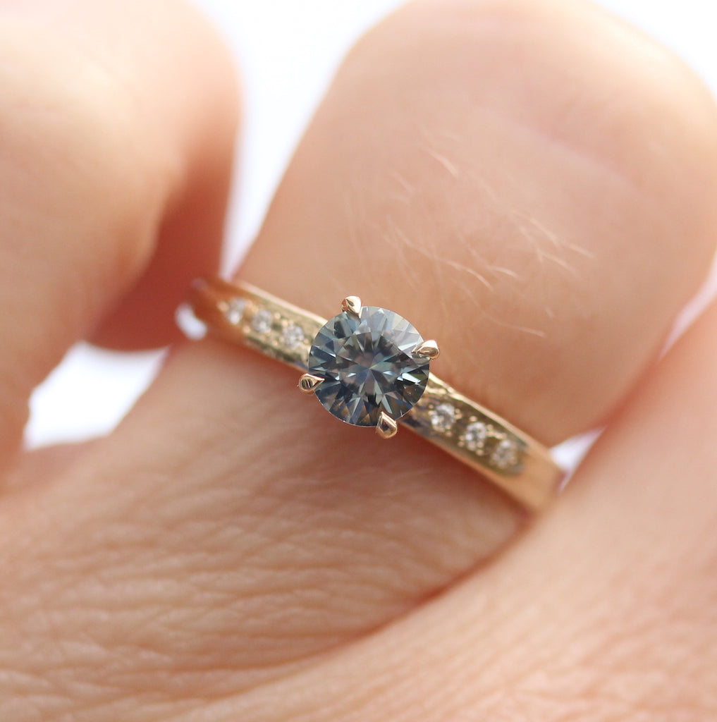 Round teal sapphire ring on the finger