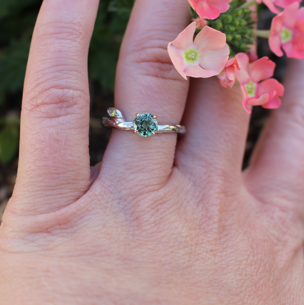 Green sapphire and white gold ring with flowers on hand