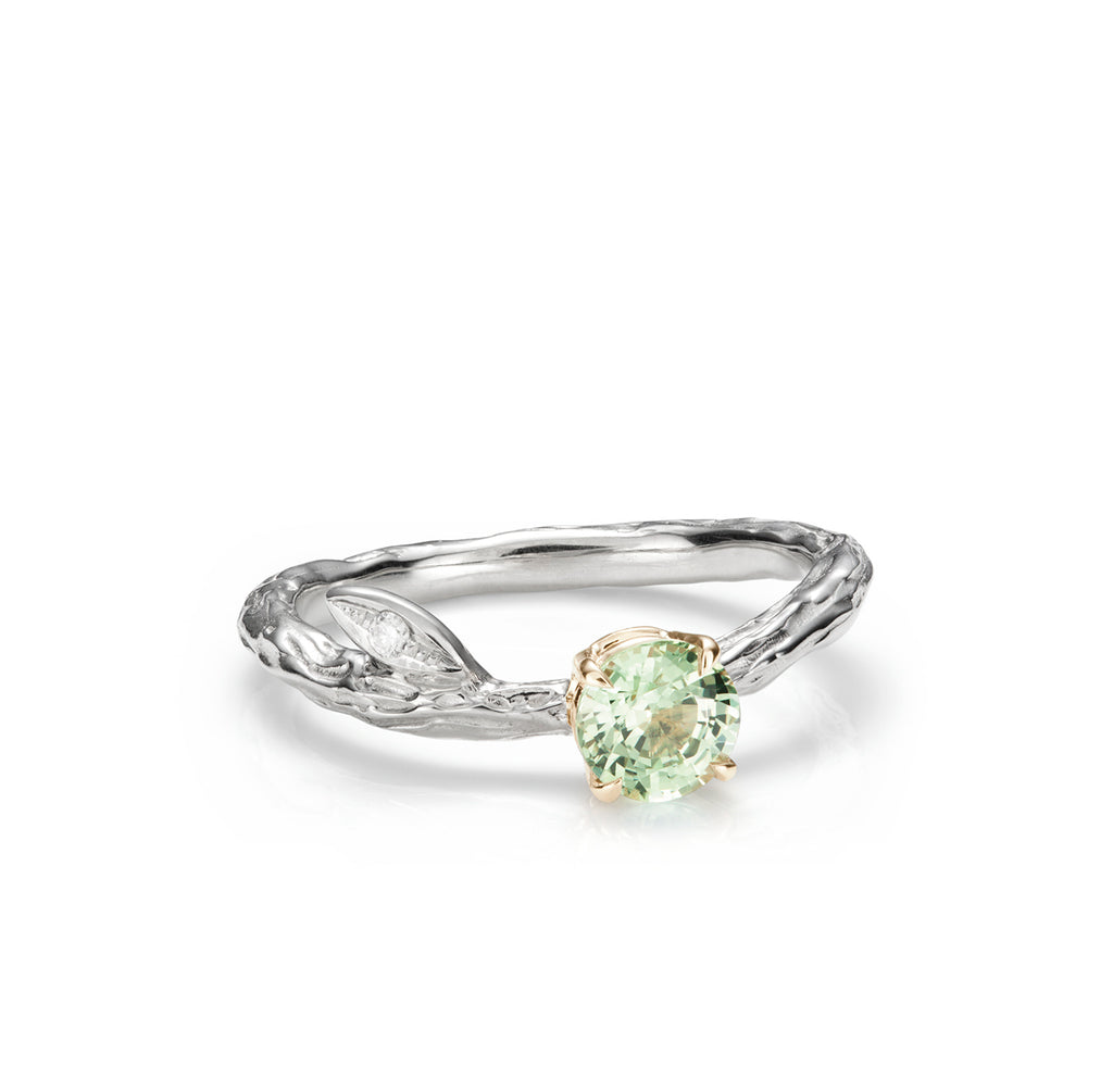 Branch and leaf ring on white background with green gemstone