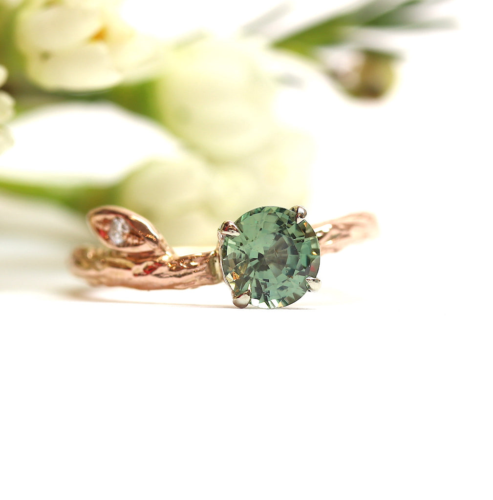 Green sapphire ring on white background with flowers